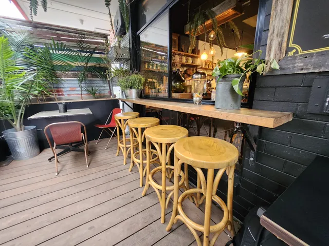 Fork And Waffle Cafe outdoor deck with yellow bamboo stools, plants, and warm interior visible through window