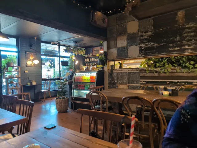Fork And Waffle Cafe dining room with bentwood chairs, display fridge, tropical plants and festoon lights